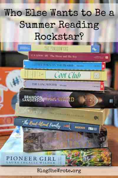 stack of books on a table in front of a bookshelf with a laptop behind it