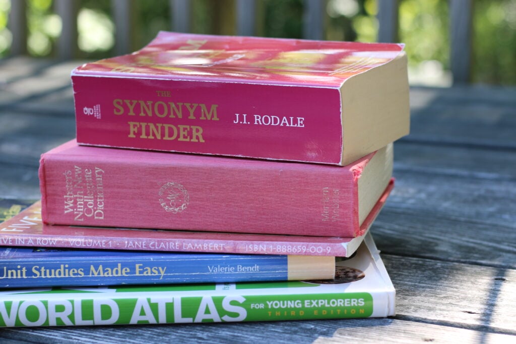 a stack of reference books, including a dictionary, on a wood surface
