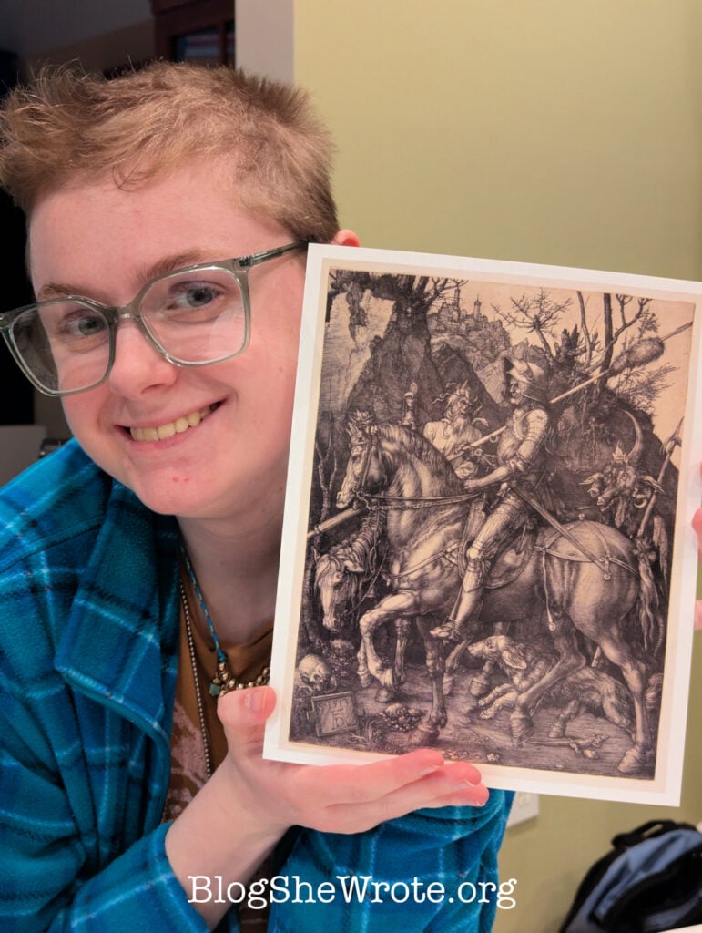 Young woman with glasses holding up a print of an etching by Albrect Duhrer